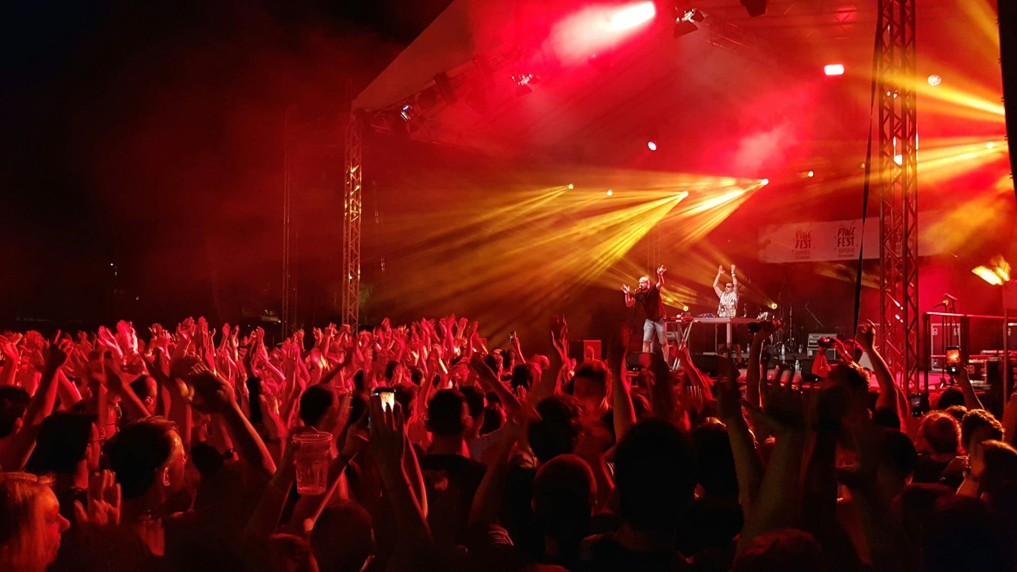 https://marketingproduccion.com/wp-content/uploads/2024/06/crowds-of-people-at-a-concert-having-fun-under-red-stage-lights-.jpg